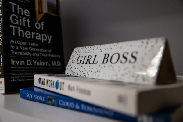 "Girl Boss" sign amongst therapeutic books